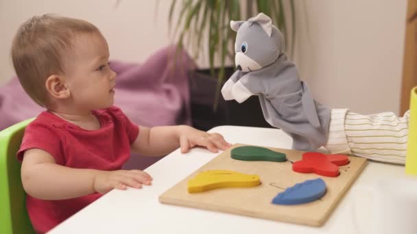 一个老师的特写用木偶向蹒跚学步的小女孩展示如何用木制彩色的方块和精美的形状玩耍 培养孩子良好的运动技能 — 图库视频影像