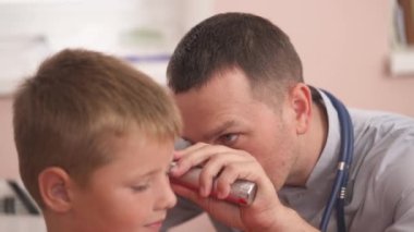 Doktor otoskop kullanarak erkek hastaların kulaklarını muayene ediyor. Otolaryngology. Pediatrik konsept. Seçici odak atışı