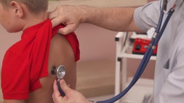 Gelişmiş bir terapistin fonendoskop kullanarak küçük çocuğun tıbbi muayenesini yaptığı yakın çekim bir gösteri videosu. Pediyatrik konsept