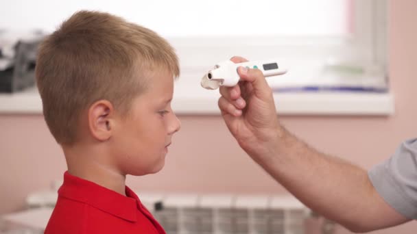 病院で赤外線温度計で少年の温度を測定医師 健康診断 — ストック動画
