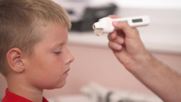 Doctor Measures Temperature Boy Red Shirt Using Electronic Infrared Thermometer — Stock Video