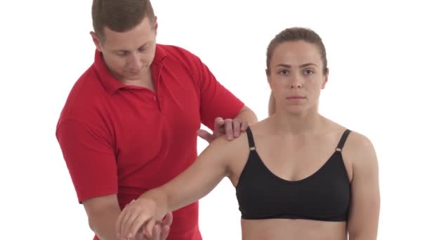 为女运动员做肩关节功能测试的按摩师的肖像 因白人背景而被隔离 — 图库视频影像
