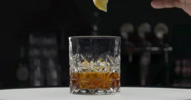 Bardaki masanın üzerinde altın alkollü bardaklar var. Tanınmayan barmen konyağa bir dilim limon ekliyor. Viski kokteyli. Cam odaklı.