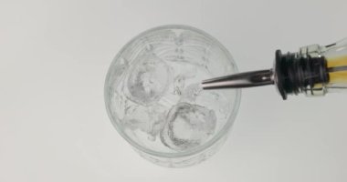 Buzlu bardağa viski dökmenin en üst görüntüsü. Şişe doldurucu kullanıyorum. Alkolik içecek. Barmen aletleri. Beyaz arkaplanda izole.