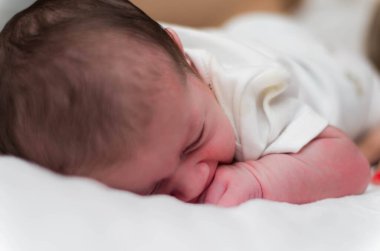 7 günlük yeni doğan bebek, bebeğin yatakta yatarken yüzünü kapat..