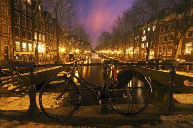 Amsterdam 'da bir ortaçağ köprüsünde geceleyin Hollanda' da bisiklet sürmek.