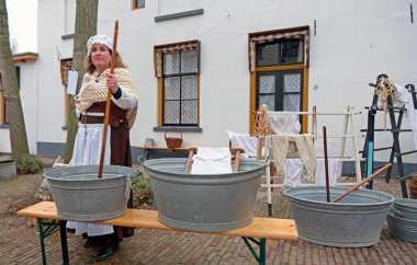 Deventer, Hollanda - 16 Aralık 2023: Dickens Festivali sırasında çamaşır yıkayan kadın ortaçağ kıyafetleri Charles Dickens 'ın ünlü kitaplarından 950' den fazla karakter Deventer, Hollanda 'da yeniden yaşıyor