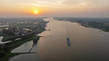 Gün batımında Hollanda 'da Loevestein şatosuyla Merwede nehrindeki bir yük gemisinden havadan.