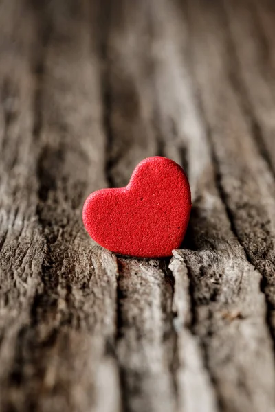 Miniature red hearth shape on the old dried plank. Old wood grain. Textured background. Valentine day concept