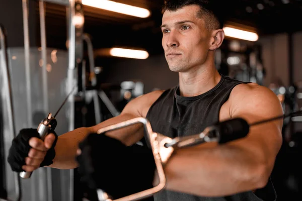 Male model working out in a modern gym with different training equipment in the background