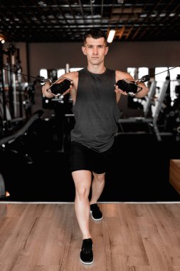 Genç vücut geliştirici ve kişisel antrenör modern, iyi donanımlı bir spor salonunda çalışıyor. Kararlılık ve odaklanma ile vücut geliştirici çeşitli egzersizler yapar, güç ve atletizm gösterir. Şey...