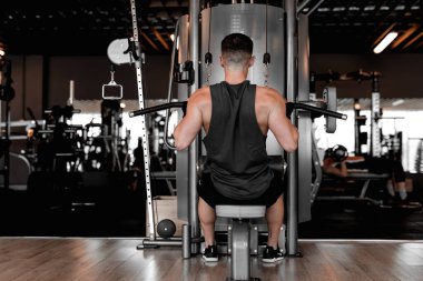 Genç vücut geliştirici ve kişisel antrenör modern, iyi donanımlı bir spor salonunda çalışıyor. Kararlılık ve odaklanma ile vücut geliştirici çeşitli egzersizler yapar, güç ve atletizm gösterir. Şey...