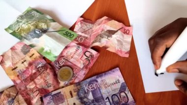Bütçeyi kağıda yazmak. Kenya 'nın banknotları arka planda. Bütçe kavramı.