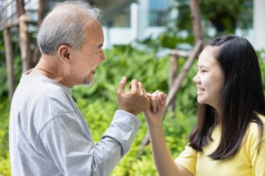 Teen girl having pinky promise with old grandfather or late-married senior father clipart