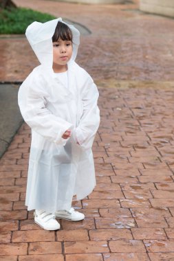 Unhappy little girl wearing raincoat feeling bad during rain fall in rainy monsoon season clipart