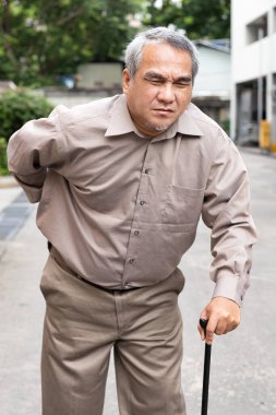 Overweighted, obese senior old man suffering from herniated disc or displaced spinal issue walking with walking aid stick clipart