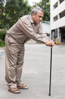 Overweighted fat senior old man suffering from serious late stage of herniated disk or displaced spinal issue walking with walking aid stick clipart