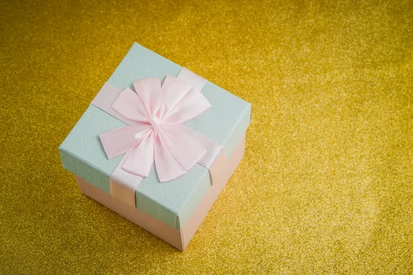 Gift in a beautiful package, box with gifts, attributes festive mood, gift on a gold background