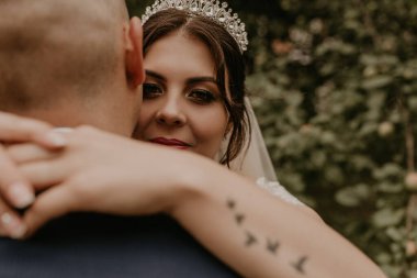 Holovchyntsi, Khmelnytska oblast, Uk raine - 07.12.2020: Gelin peçesinde ve başında bir taç ile damada sarılıyor ve kadın kolundaki dövmede uçan kuş şeklinde gülümsüyor.. 