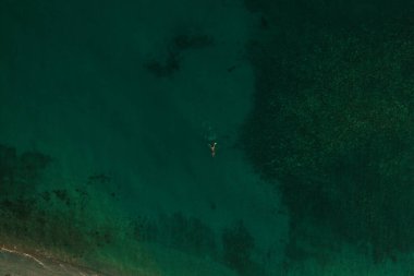 Trakya 'nın yeşil turkuaz denizi Ellada' nın üzerindeki havadan doğa manzarası. Güzel, genç bir kadın bikini tek başına okyanus suyunda yüzüyor. Şnorkelle yüzmek için maske takan kız. geniş panoramik manzara denizcisi