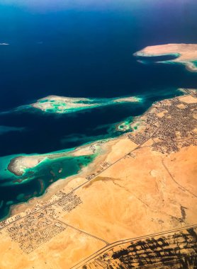 Mısır 'ın çöl adalarındaki uçak kıyı şeridinden gökyüzü manzarası. Kızıl Deniz Sharm Al Sheikh Mısır. Kuş gözü uçak penceresi dağlarına inanılmaz bir atış. Seyahat konsepti. Okyanus üzerinde uçan uçak