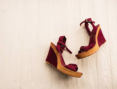Şık kama ayakkabılar, bordo ayakkabılar. Yaz arkaplan modeli metni. Beyaz ahşap arkaplanın üstündeki desen görüntüsü. Yaz moda aksesuarları plajı. Kadınlar yaz tatili Top view konsepti