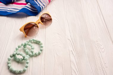 Güneş gözlüğü bijouterie mücevher bilezikler el çantası. Yaz arkaplan modelleme şablonu. Beyaz ahşap arkaplan üzerinde üst manzara. Yaz moda aksesuarları plajı. Kadın tasarımı. Tatil kavramı