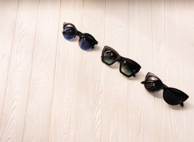 Şık siyah güneş gözlükleri. Yaz arkaplanı şablon metni. Beyaz ahşap arkaplanın üstündeki desen görüntüsü. Plaj için yaz aksesuarları. Kadınlar güneş gözlüğü tasarlar. Tatil kavramı