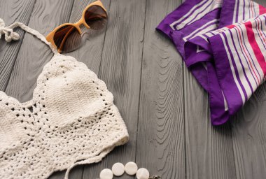 İki parçalı mayo mayo giyen beyaz örülü bir kadın. Moda gözlüğü takıyor. Yaz arkaplan şablonu maket uzay şablonu örnekleme metni. Gri ahşap arkaplanın üstü.