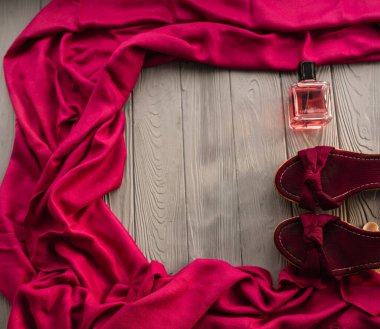 Burgundy sandaletleri şalları ve pembe parfümleri. Yaz arkaplan şablonu modelleme boş alan deseni renkli kompozisyon örneği metni. Gri ahşap arka plan üzerinde üst görünüm düz yatıyordu