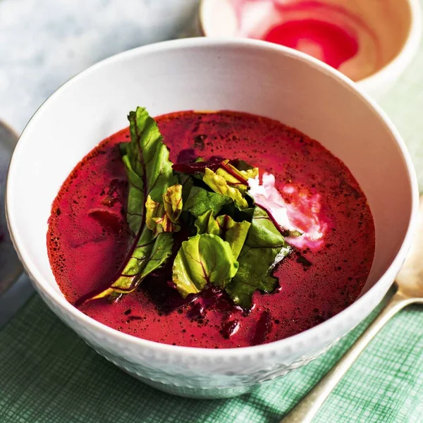A bowl of healthy beetroot leaf soup with cream on a table
