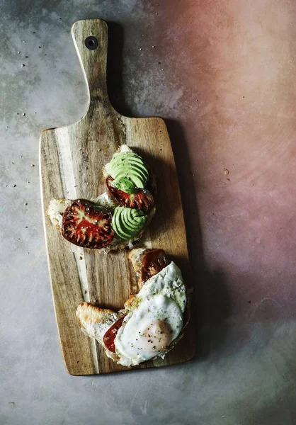 stock image Croissant with tomatoes and avocado on a chopping board