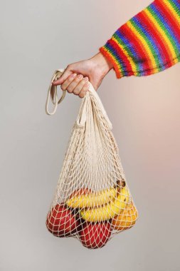 Meyve taşımak için ağ torbası kullanan bir kadın.