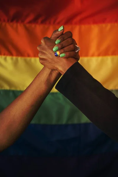 男同性恋夫妇手牵手在彩虹旗前表示支持和爱 — 图库照片