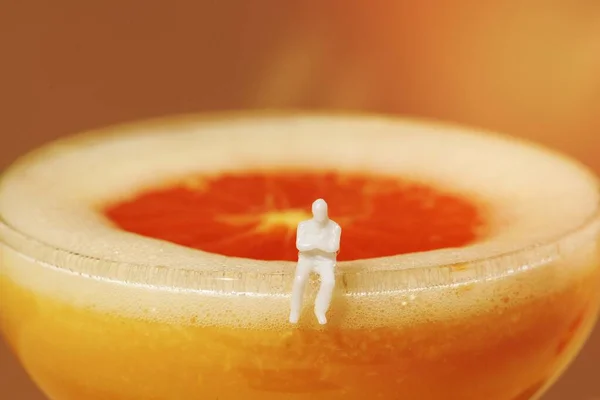 Maleńki Człowiek Siedzi Krawędzi Pomarańczowego Koktajlu Margarity — Zdjęcie stockowe