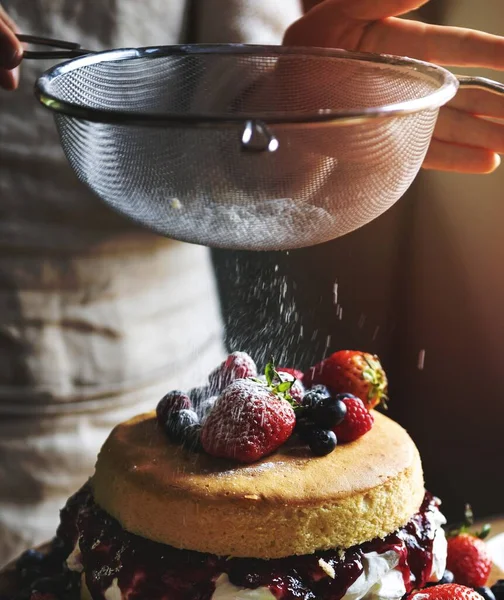 stock image Woman sieving white powder over a layered cake