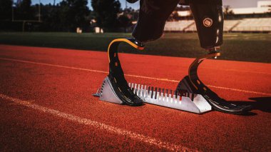 Athlete with prosthetic legs on sprint starting block  clipart