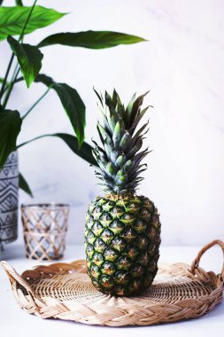 Beyaz masada örülmüş bambu tabakta ananas.