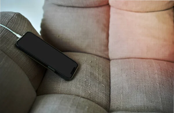 モックアップ画面スマートフォンは ソファに充電ラインを接続します — ストック写真