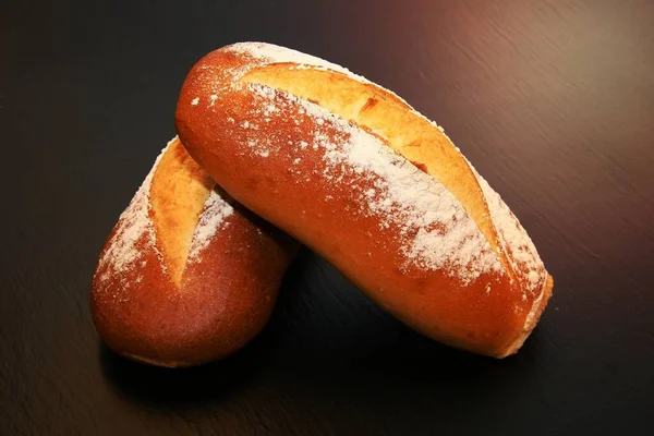 Δύο Ψημένα Ψωμιά Στη Μαύρη Επιφάνεια — Φωτογραφία Αρχείου