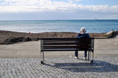 Lonely man on the bench near the sea