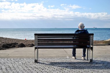 The man is sitting alone on the bench