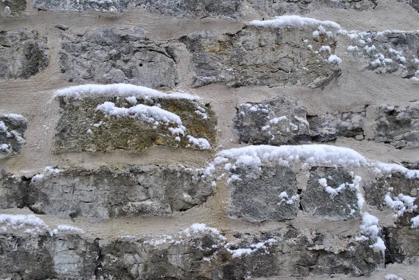 a large white wall with snow and the remains of stones on the rock