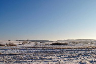 Mavi gökyüzü ve beyaz bulutlu karlı bir tarla.