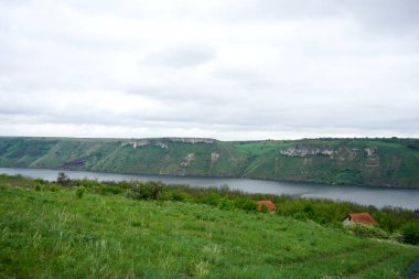 Dağları ve bulutlu gökyüzü olan bir göl manzarası.