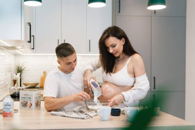 Evde, mutfakta, yatakta, pencerenin yanında ve banyoda, dişlerini fırçalarken, ellerini karnına koyup, un parçasından cheesecake yaparken,