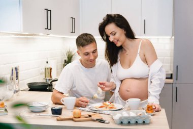 Evde, mutfakta, yatakta, pencerenin yanında ve banyoda, dişlerini fırçalarken, ellerini karnına koyup, un parçasından cheesecake yaparken,