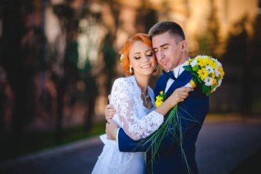 Mavi takım elbiseli, beyaz elbiseli ve buketli güzel bir çift.