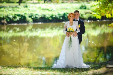 Mavi takım elbiseli, beyaz elbiseli ve buketli güzel bir çift.