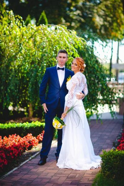ブルーのスーツを着た若い美しいカップルとホテルの花束付きの白いウェディングドレス — ストック写真